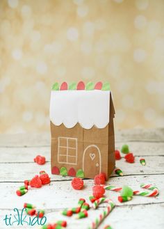 a brown paper bag with a gingerbread house on it surrounded by sprinkles