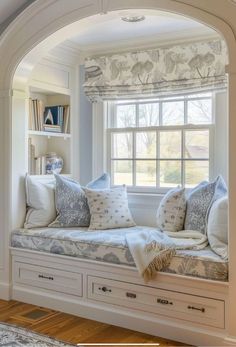 a window seat with pillows on it in front of a book shelf and bookshelf