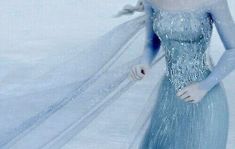 a woman in a blue dress is walking through the snow with her long flowing veil