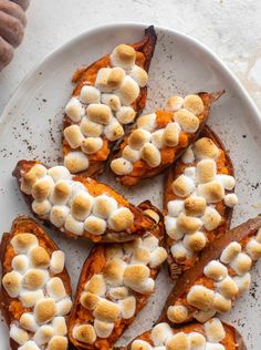 baked sweet potatoes topped with marshmallows on a white plate, ready to be eaten