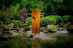 a wooden door sitting in the middle of a pond surrounded by rocks and trees with water running through it