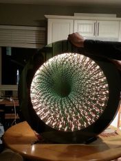 a man holding up a large circular object in his hands with fireworks coming out of it