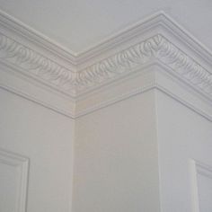 the corner of a room with white walls and molding on the ceiling above it