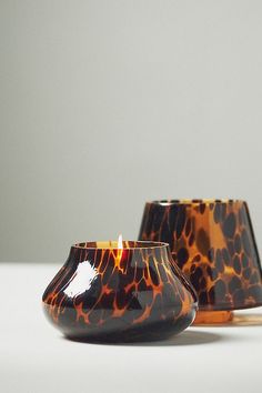 two brown and black vases sitting next to each other on a white counter top