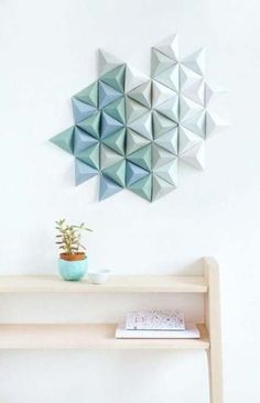 three origami pieces are hanging on the wall above a table with a plant