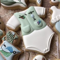 decorated cookies are arranged on a table with white and green icing, including baby ones