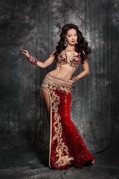 a woman in a red and gold belly dance costume with her arms out to the side