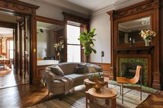 a living room filled with furniture and a fire place in front of a mirror on the wall