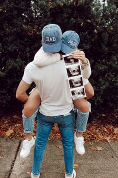 a man holding a woman on his back while they both wear dad's hats