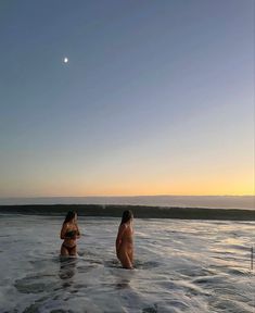 two women in the ocean at sunset