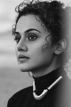 a black and white photo of a woman with curly hair wearing a collared top