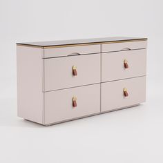 a white dresser with gold handles and knobs on the top, against a white background