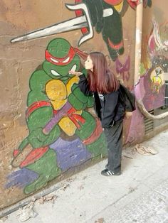 a woman standing in front of a wall with teenaged ninja turtles on it's side