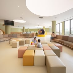 two children sitting on different colored couches in a large room