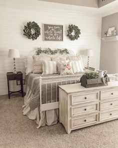 a bedroom with white walls and furniture in the corner, along with wreaths on the wall