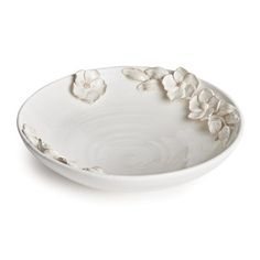 a white bowl with flowers on the rim and saucer in the middle, isolated against a white background