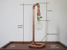 a table lamp with copper pipes and a light bulb on the base, labeled in description