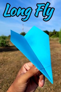 a hand holding a blue paper airplane with the words long fly in front of it