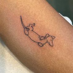 a small tattoo of a dog on the arm with a long tail that is curled up to it's neck