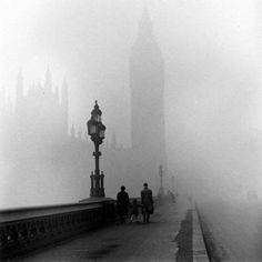 two people walking on a foggy bridge with big ben in the background, london