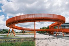 an orange bridge over a walkway in a park