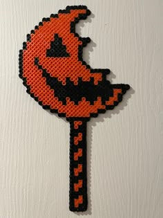 an orange and black beaded key on a white wall