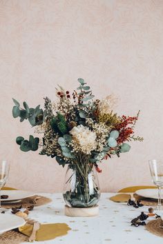 a vase filled with lots of flowers on top of a white tablecloth covered table