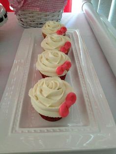 three cupcakes with white frosting and pink icing