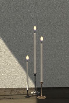 three white candles sitting on top of a wooden table next to a wall and floor