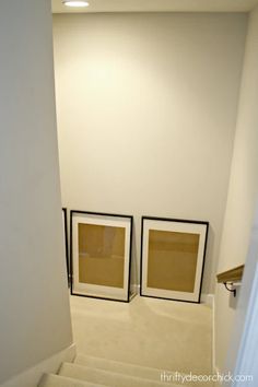 two framed pictures sitting on the wall next to each other in a room with white walls