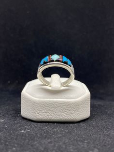 Contemporary handmade Native American Navajo inlay sleeping beauty turquoise, white fire opal, ox blood coral & Jet sterling silver mens band ring Size 12.5 stamped & signed by artist Rick.T This ring is made with the famous Navajo style; Inlay Inlay is the process of hand-cutting each stone to fit in a flush surface. As you can see, the stones are also slightly raised to give it a textured feeling. There are 25 hand cut stones soldered and inlayed into a silver bezel with gorgeous silver work s Mens Band Rings, Navajo Style, Silver Work, Sleeping Beauty Turquoise, Mens Band, Sterling Silver Mens, Ox, Fire Opal, Band Ring