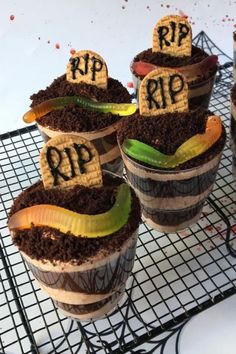 four cupcakes decorated to look like barrels with dirt on them and the words rip spelled in small letters