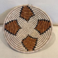 a brown and white woven basket sitting on top of a table next to a wall