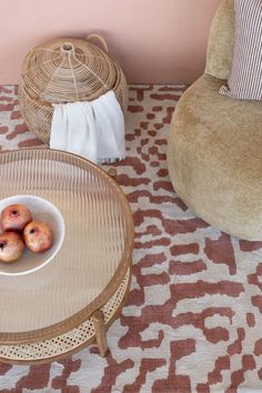 two donuts are in a bowl on a table next to a chair and rug