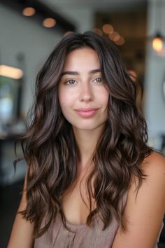 Woman with long wavy brown hair smiling softly in a modern, softly lit interior. Mid Tone Brown Hair, Low Dimensional Brunette, Dark Brown Hair Neutral, Dimensional Brunette Balayage Dark Brown, Dark Brown With Natural Highlights, Autumn Brunette, Dimensional Brown Balayage, Rich Brown Dimensional Hair, Dark Brown Hair With Highlights Pale Skin