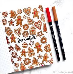 an open notebook with ginger cookies and christmas decorations on it, next to two markers