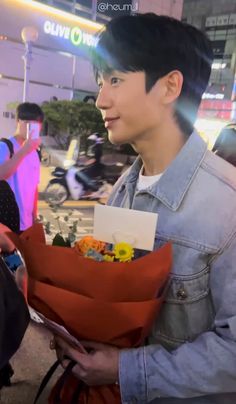 a young man holding flowers in his hands