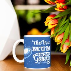 the best mum in the galaxy coffee mug sits next to some orange tulips