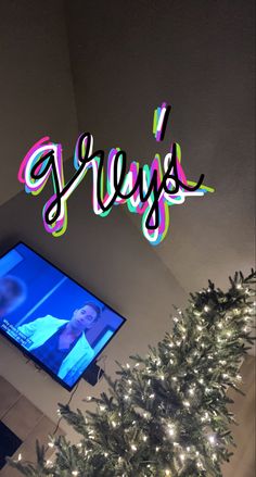 a christmas tree with the word glyyss on it in front of a flat screen tv