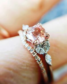 a woman's hand with a pink diamond ring on top of her finger and two white diamonds around the band