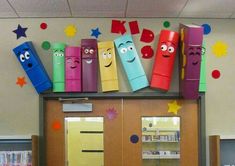 an office cubicle decorated with colorful crayons and paper faces on the wall