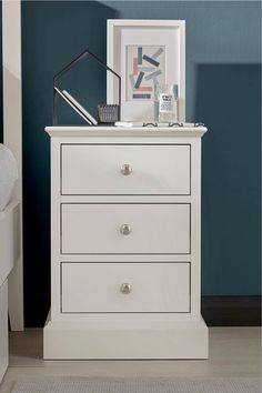 a white dresser with three drawers in a room