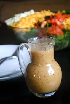 a glass pitcher filled with liquid sitting on top of a table next to a salad