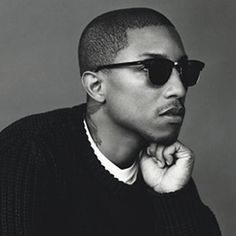 a man wearing sunglasses and a sweater posing for the camera with his hand on his chin