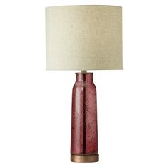 a red table lamp with a white shade on the base and a beige linen lampshade