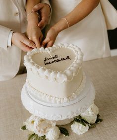 a newly married couple cutting their wedding cake with the word just married written on it