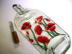 a glass bottle with red flowers on it and a pen in the bottom one side