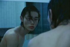 a shirtless man looking at himself in the mirror