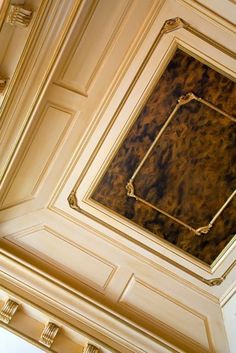 the ceiling in this room is painted gold and has a square shaped painting on it