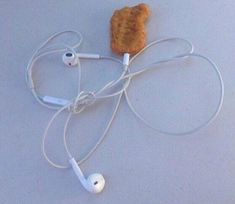 a piece of bread and headphones are on the floor with earbuds attached to it